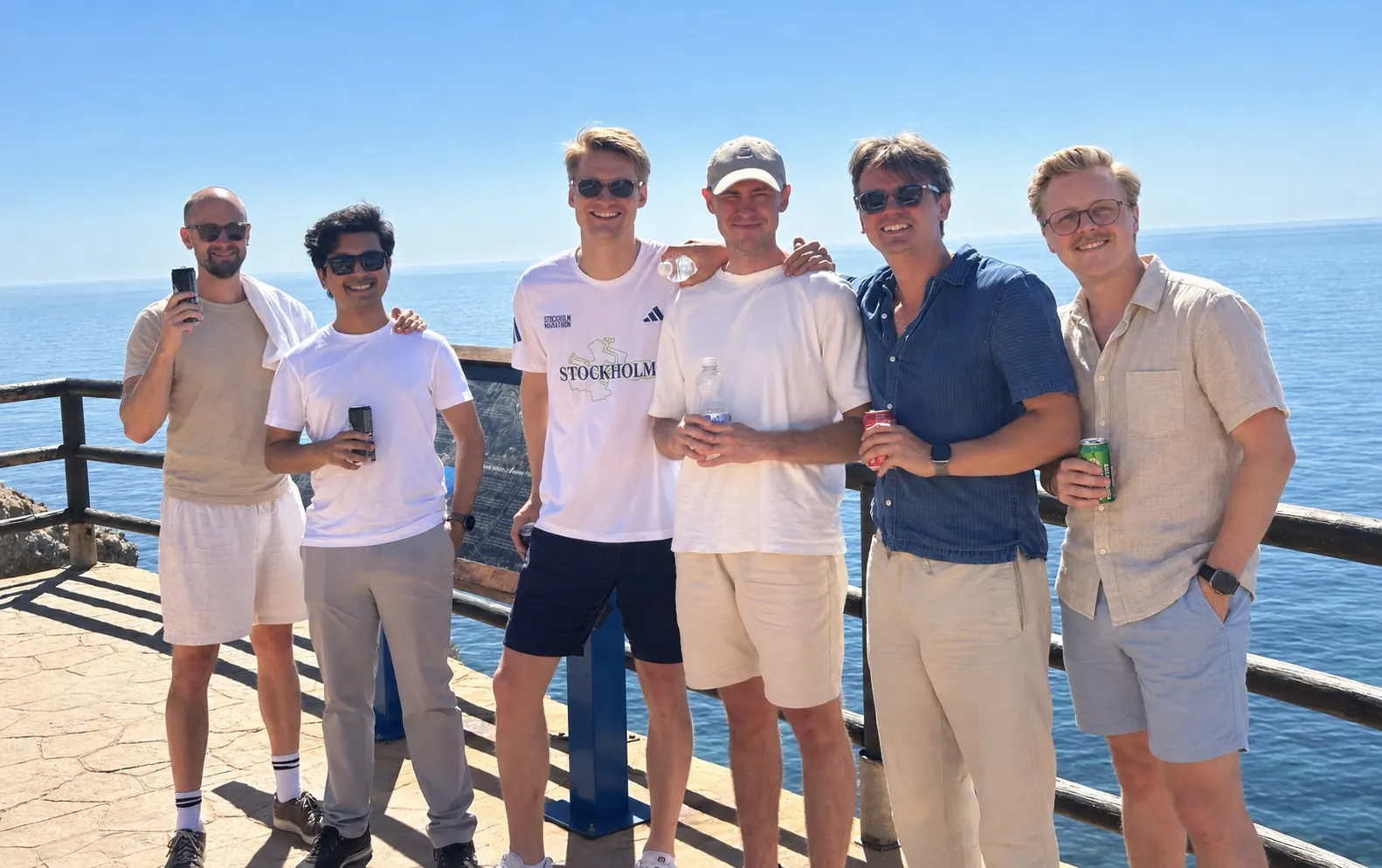 Sex kollegor på ett utsiktsdäck vid havet en solig dag på kickoffen i Málaga.